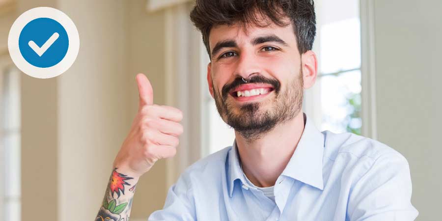 Man with tattoo arm sleeve making thumbs up sign.