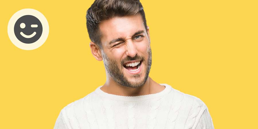 Cute young man with a beard wearing a white tshirt winking cheekily