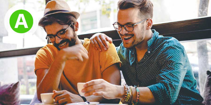 Two handsome gay men with beards sharing a laugh over coffee.